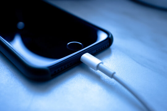 iPhone 7 is connected to the charger. The iPhone 7 smartphone is charged using a white cable