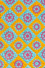 Top view of crochet afghan, made of colorful granny square motifs of yellow, turquoise and lilac colors. - obrazy, fototapety, plakaty