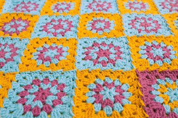 Fototapeta na wymiar Side view of multicolored crochet granny squares, seamed together in a blanket.