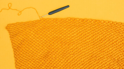 Huge piece of yellow crochet net with a hook in it.