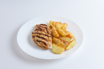 Tasty grilled chicken fillets on white plate with potatoes. Isolated on white background, top view