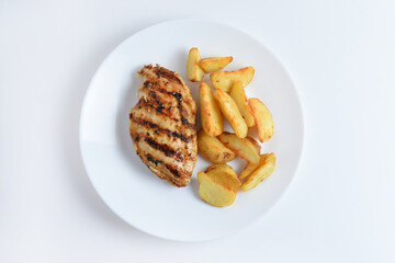 Tasty grilled chicken fillets on white plate with potatoes. Isolated on white background, top view