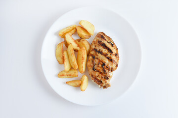 Tasty grilled chicken fillets on white plate with potatoes. Isolated on white background, top view