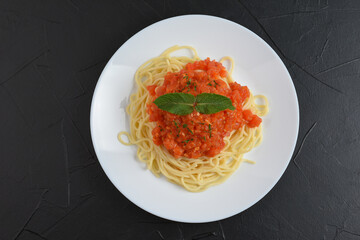 Top view of plate with spaghetti in tomato sauce and basil. Copy space for text