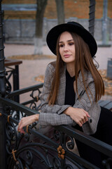 romantic beautiful brunette smiling girl in a black hat walking in the autumn city