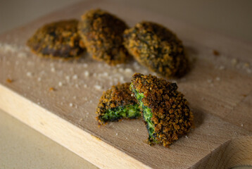 Spinach fritters or latkes with breadcrumbs on a wooden cutting board 