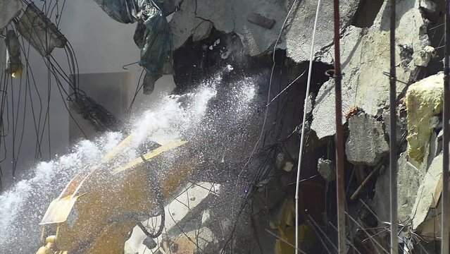 Slow motion of falling down broken roof tiles and planks during demolition of a house. Hydraulic arm pounding and crushing the roof. An excavator turns old home into rubble and dust fills the air. SM
