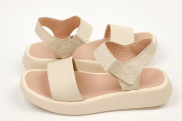 Pair of beige leather women's sandals on a white background, close-up. Fashionable women's shoes. Casual shoes.