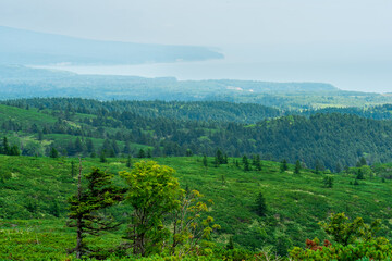 typical landscape of the southern Kuriles, view of Kunashir Island from the slope of Golovnin volcano, slope of Mendeleyev volcano is visible in the distance in the haze
