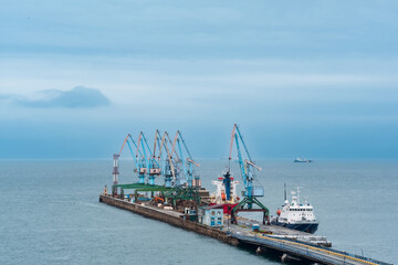 cargo berth with port cranes and moored ships against the backdrop of the open sea