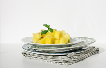 Pieces of ripe yellow watermelon and mint on vintage plates and white background