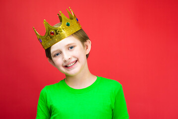 portrait of a happy boy in a golden crown on a red background
