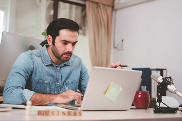 Portrait of serious businessman with laptop sitting at desk in office. Cheerful casual caucasian employee, Handsome businessman using mob phone. successful business working at office. mobile phone.