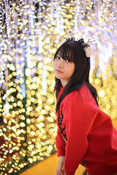 Beautiful Asian young woman with a red sweater with Christmas tree light