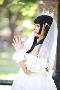 Beautiful young woman with white lolita dress with european garden Japanese fashion