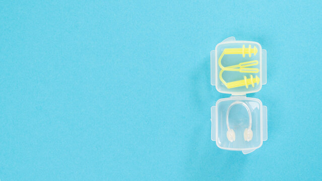 Nose clip and swimming earplug in a transparent case on a blue background