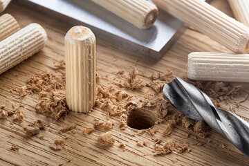 drill bit makes hole in wooden oak board for wooden dowel.