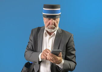 A male train conductor looks through information on a device. On a blue background.