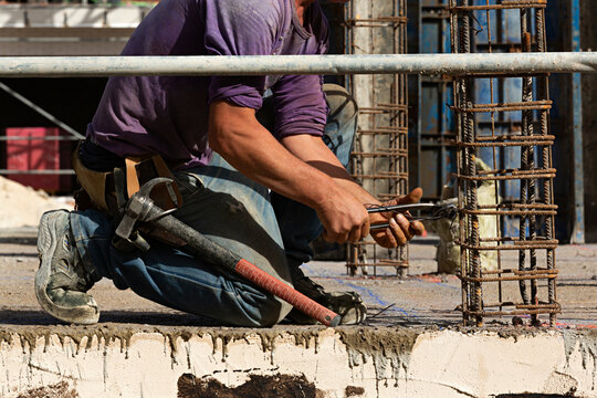Obrero trabajando agachado en una obra de construcci&oacute;n.