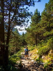 Fototapeta na wymiar Woman summer hiking with backpack and trekking clothes in Vall de Nuria, Catalonia Pyrenees. Day trek outdoor enjoying nature and adventure. Mountain climbing active and healthy lifestyle.