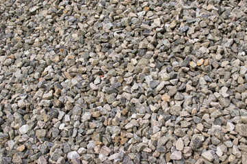 A large pile of small granite stones fills the image, outdoors in the morning.