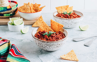 Chili con carne in a clay bowl on a concrete or stone rustic background- traditional dish of mexican cuisine.Top view.
