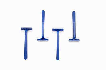 Four blue plastic razors on a white background in the center. Disposable blue plastic razors lie on a white background. Shaving and care product for smooth skin. Razor without replaceable blades