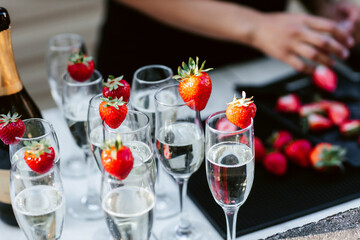 Open buffet with glasses of champagne and garnished with strawberries. Alcoholic drinks with ripe strawberries during the party. Public event for adults