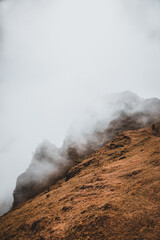 Mist and fog rising over mountains on Madeira, with dry meadows in the foreground