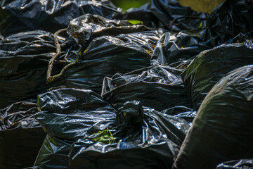 Garbage bags next to the trash can. Black plastic bag texture and background.