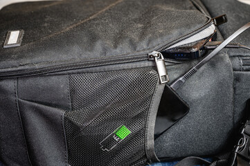The smartphone is charged from the power bank lying next to it in a backpack. Modern technology concept © Marina Gordejeva