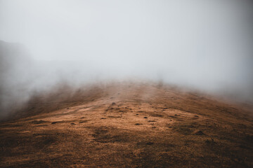 Mist and fog rising over mountains on Madeira, with dry meadows in the foreground