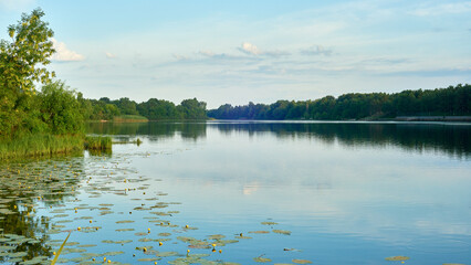 Scenic evening landscape on the river with clouds on the blue sky.