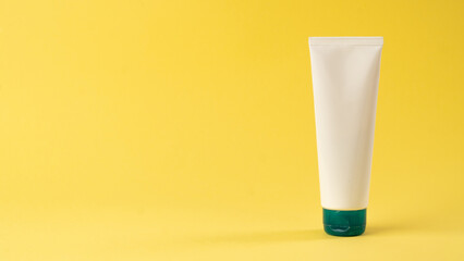 A tube of face or hand cream on a yellow background with space for label and text