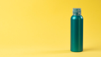 Turquoise bottle with cosmetic on a yellow background with space for text and label