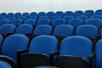 Naklejka premium Rows of several blue chairs in an auditorium, or theater, with no person and all seats the same.