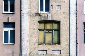 The old window in the building is boarded up with wooden sheets from the inside