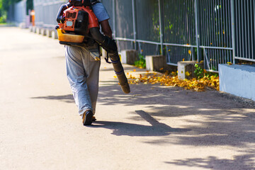 A worker removes yellow foliage with a knapsack windblower