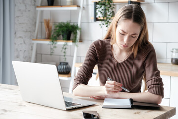 Head shot portrait of young woman writing, taking notes, female student sitting at work desk with laptop, studying online, webinar, confident businesswoman working with documents, freelance workday