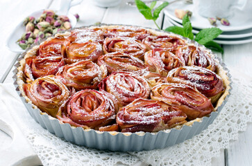Traditional French apple tart aux pommes bouquet de roses served as close-up on a cake plate