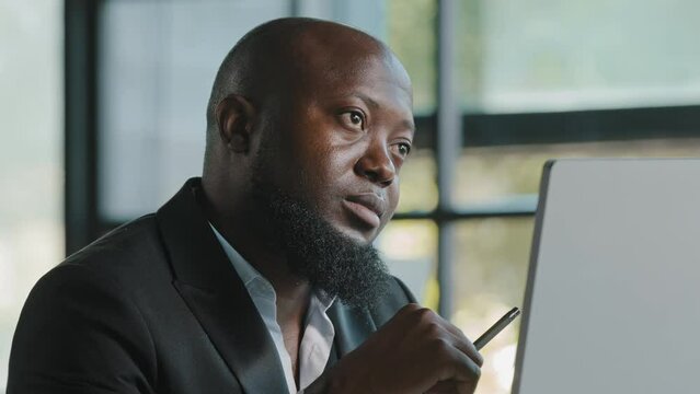 Doubtful thoughtful african american team leader male coach think question solve daily working task in mind has dilemma self brainstorming reflective turns pen by hand create project business strategy
