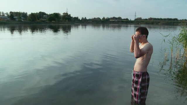 Young Guy Puts On Swimming Goggles, He Is Going To Swim In The Lake