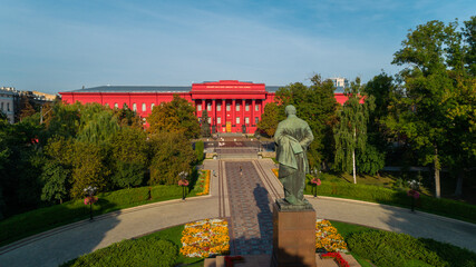 Aerial view back view statue of the writer Taras Grigorovich Shevchenko in park on a sunny spring day. Drone shot red building facade Kyiv National University of Taras Shevchenko. Capital of Ukraine - obrazy, fototapety, plakaty