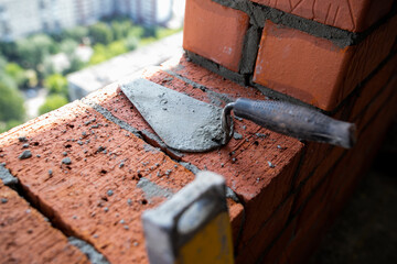 Close up of industrial bricklayer installing bricks on construction site
