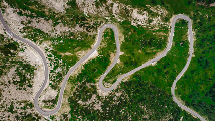 Winding road from high mountain pass in Dolomites, Italy. Great road trip through dense woods and...