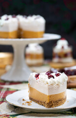 Christmas pumpkin and cranberry mousse on cake stand, on a festive table