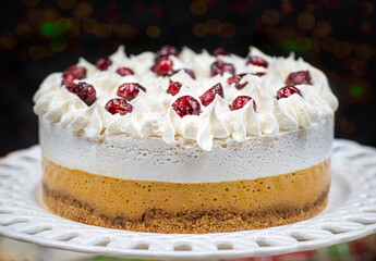 Christmas pumpkin and cranberry mousse on cake stand, on a festive table