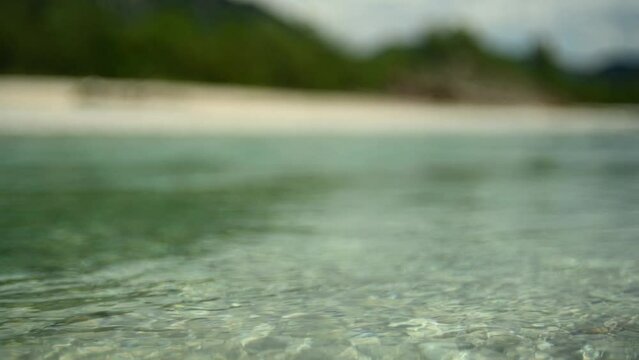 Slow motion of a river with turquoise water in summer, shot with an open aperture and a lot of bokeh.