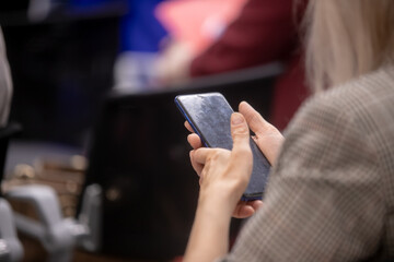 Audience in the conference hall. The man in the foreground looking into your phone