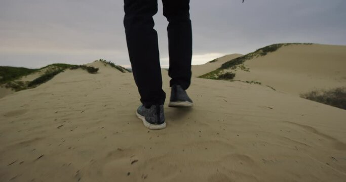 Man walks on sand dunes with camera at Oceano Dunes SVRA at Pismo Beach, California